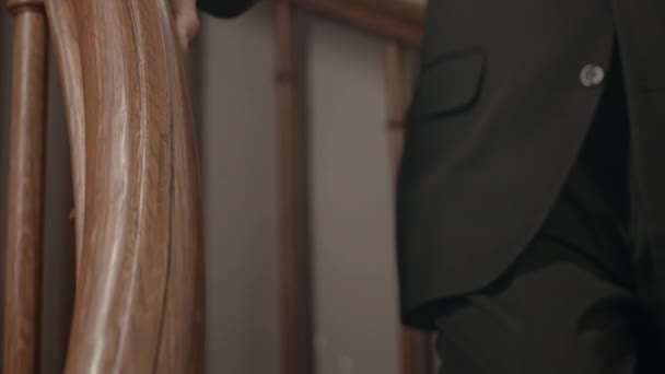 教会の木製の階段の手すりに手を傾けるスーツの認識できないカトリック司祭の閉鎖 — ストック動画