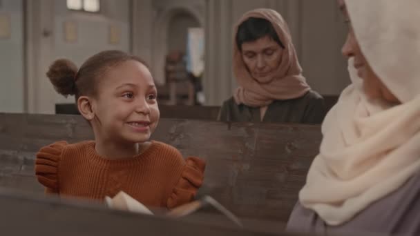 在宗教仪式期间 与祖母坐在天主教堂木制长椅上的非洲裔美国小女孩 — 图库视频影像