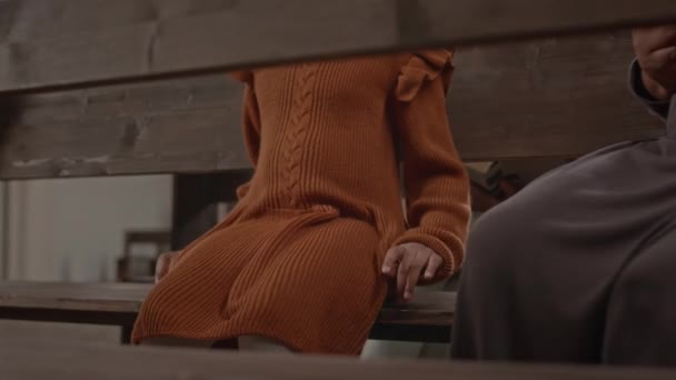 在教堂参加宗教仪式时 一个无法辨认的小女孩在木制长椅上敲着手指头 被截断的照片 — 图库视频影像