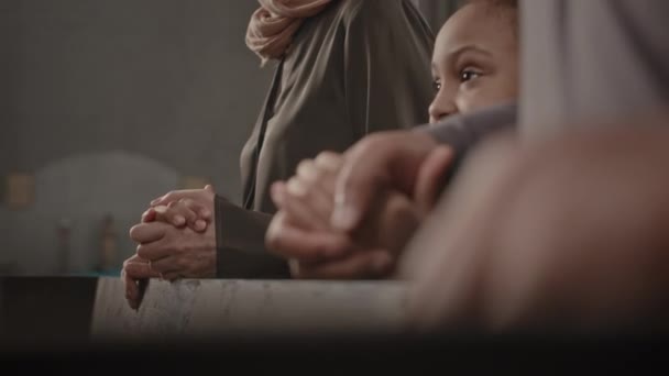 カトリック教会のベンチで家族と一緒に立っている間 小さなアフリカ系アメリカ人の少女が説教を聞いている — ストック動画