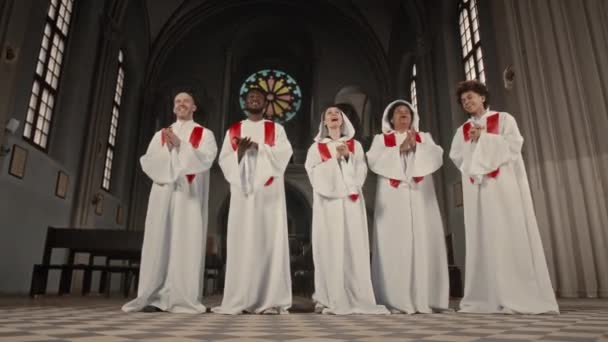 在天主教教堂表演的时候 全长的多种族唱诗班穿着长长的白色长袍拍手唱歌 — 图库视频影像
