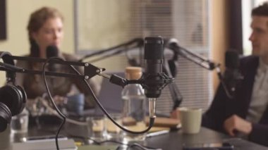 Profesyonel podcast stüdyosunda bayan radyo sunucusu ve konuk sohbeti odaklanmış arka planda mikrofon ekipmanıyla