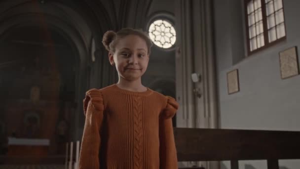 가톨릭 교회에서 카메라를 귀여운 오렌지 드레스에 아프리카계 미국인 소녀의 초상화 — 비디오