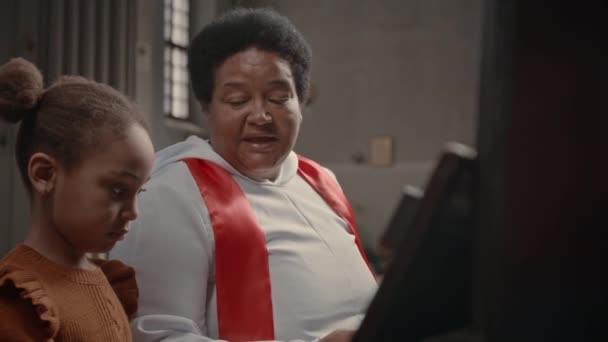 Африканська Американська Бабуся Навчає Онуку Грати Фортепіано Католицькій Церкві — стокове відео
