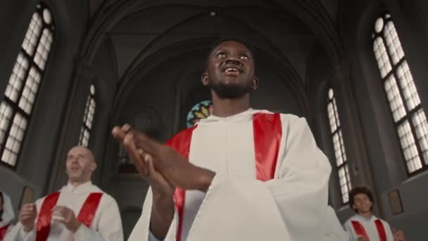 年轻黑人男子与其他唱诗班成员在天主教堂表演的低角度 — 图库视频影像