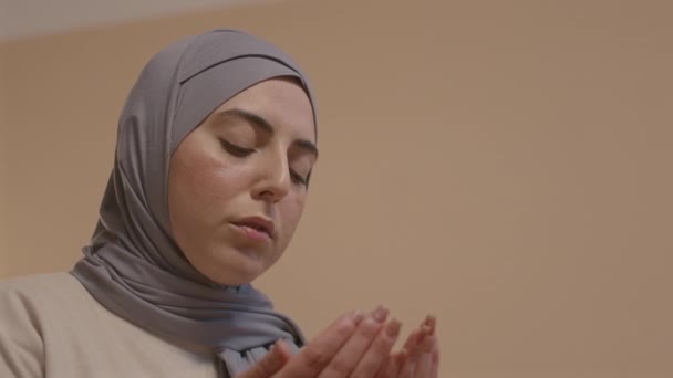 ヒジャーブの若いムスリム女性の低い角度は 自宅だけで祈りを読んでいる間 彼女の手のひらを見て — ストック動画