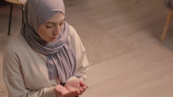 年轻的穆斯林妇女在客厅地板上祈祷时保持手掌向上的头像 — 图库视频影像
