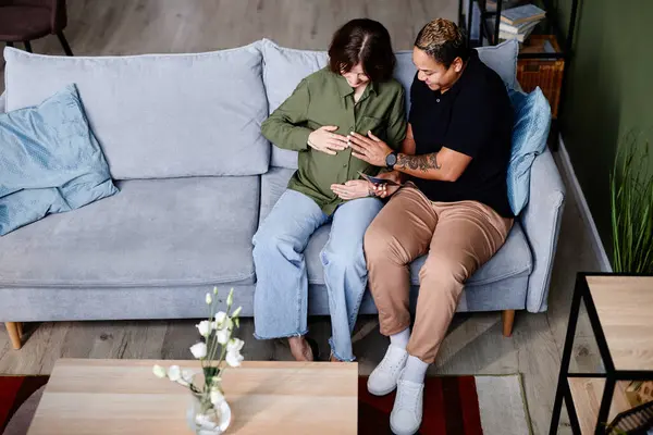 现代同性恋夫妇与怀孕的年轻女子在家中观看婴儿照片的高角镜头 复制空间 — 图库照片