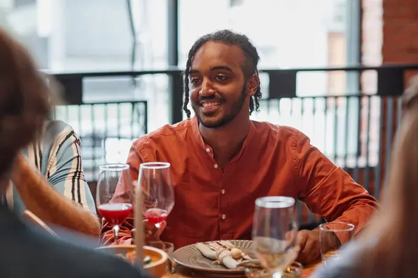在舒适的气氛中 年轻黑人男子在餐桌上与朋友交谈的肖像 — 图库照片