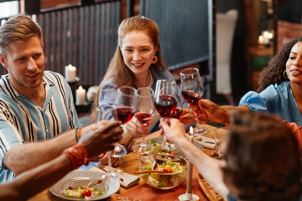 在舒适的环境中 年轻人一边在餐桌边享用晚餐 一边碰碰酒杯的高透视 — 图库照片
