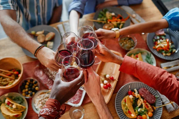 一緒にディナーパーティーでお祝いしながらワイングラスを試飲する若者のトップダウンビュー スペースをコピー — ストック写真