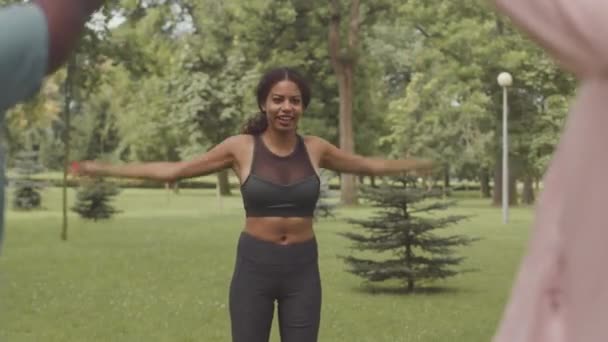 野外夏季训练期间 身穿紧身黑色运动服的年轻女子健身教练进行大臂弯热身运动 — 图库视频影像