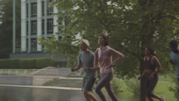 Pan Średnie Spowolnienie Młodych Wielonarodowych Sportowców Biegających Razem Parku Letni — Wideo stockowe