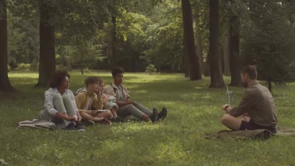 공원에서 생태와 환경에 수업을하는 다인종 학생의 그룹에 모델을 보여주는 코카서스 — 비디오