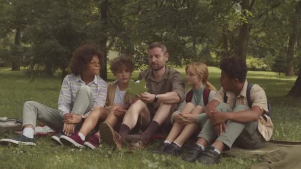 Kafkas Erkek Öğretmen Çeşitli Çocuklar Grubuyla Büyüteç Altında Yeşil Ağaç — Stok video