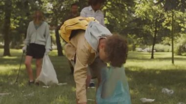 Okul arkadaşları ve öğretmeni olan melez bir çocuk yazın parktaki çöpleri toplayarak çevreye yardım ediyor.