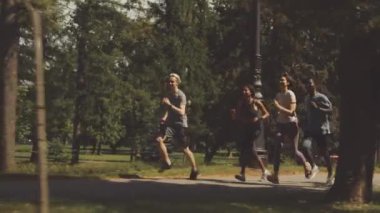Yaz günü parka birlikte koşan dört genç sporcunun tam boy yavaşlığı.