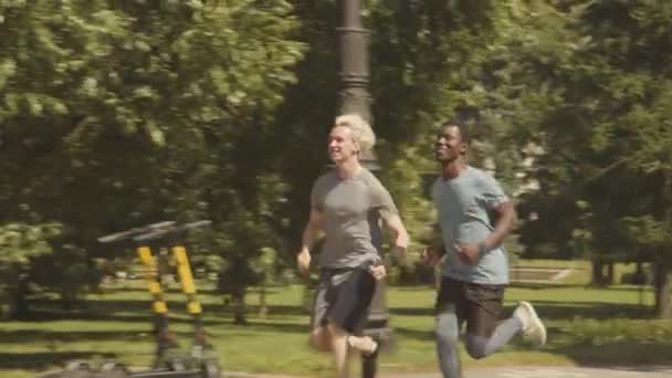 Track Shot Dwóch Różnych Przyjaciół Mężczyzn Biegających Parku Ciepły Słoneczny — Wideo stockowe