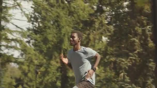 Трек Середній Знімок Активного Молодого Чорношкірого Спортсмена Працює Сонячному Громадському — стокове відео