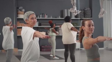 Stüdyoda grup yogası yapan çeşitli çok nesilli kadınların orta boy fotoğrafları.