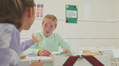 Ders sırasında iki beyaz liseli kızın fısıldaşması.