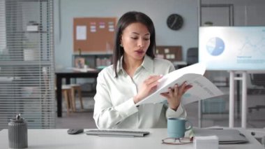 İş yerindeki iş yerinde kameraya konuşan grafikler ve diyagramlarla mali rapor tutan çekici genç iş kadınının bel ponksiyonu.