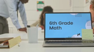 Değişik 6. sınıf öğrencileri ve onların siyah erkek öğretmenlerinin eğitici slayt sunumuyla birlikte ön plandaki dizüstü bilgisayarda etkileşimli matematik dersi aldıkları PAN görüntüleri.