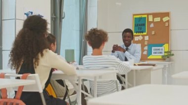 Modern bilişim dersinde Afrikalı Amerikalı erkek öğretmen çok ırklı öğrencilere kodlama ve programlamanın temellerini anlatıyor.