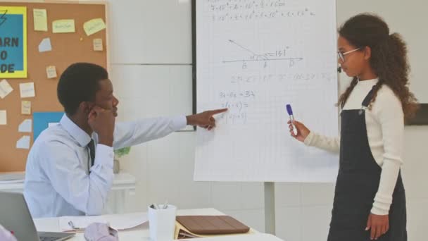 教室で数学の問題を解決するスマートなアフリカ系アメリカ人の女子生徒のミディアムショットと黒人の男性教師の助け — ストック動画