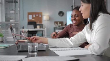 Dizüstü bilgisayarda iş sunumuna bakan ve iş yerinde tartışan iki farklı genç iş arkadaşının belini kaldırın.