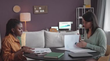 Çok ırklı iki genç iş ortağının ofis toplantısı sırasında sözleşmeyi okuduktan sonra tokalaşırken orta boy fotoğrafı.