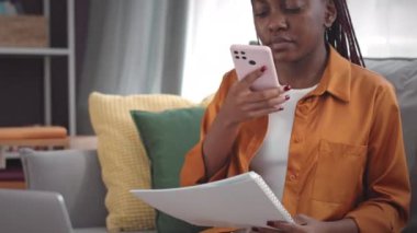 Çalışırken akıllı telefonuyla iş belgelerinin fotoğrafını çeken genç siyahi bir kadının belini kaldırın.