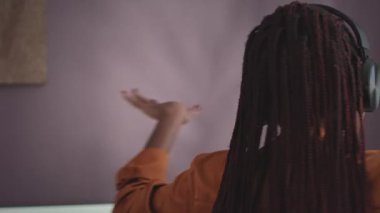 Genç enerjik siyahi kadının kablosuz kulaklıklarla müzik dinleyip hafta sonları evde yalnız başına dans ederken orta boy yakın çekimi.