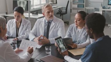 Çağdaş tıp kliniğinde toplanan çok ırklı doktor ve olgun Kafkas erkek başhekiminin belini kaldırın.