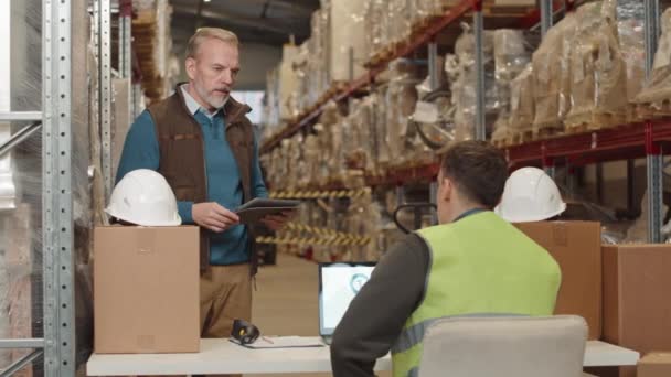 大きい倉庫で一緒に働いている間商品の交通機関を論議する2人の専門の商品の専門家の中型ショット — ストック動画