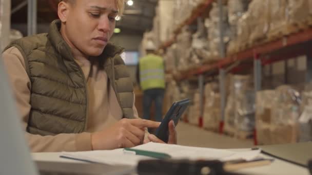 職場で在庫管理をしながらスマートフォンを使用した若手プロの女性倉庫マネージャーを待つ — ストック動画