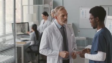 İş yerinde el sıkışan iki farklı erkek meslektaşın orta boy fotoğrafı.