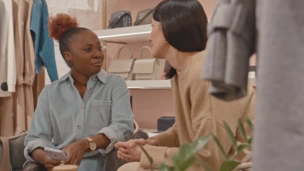 ラグジュアリーデザイナーショールームで服を買い物しながら2人の若い多様な女性がチャット — ストック動画