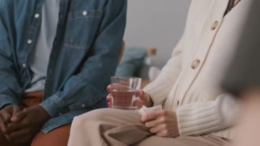 Grup terapisi sırasında elinde bir bardak su ve kağıt mendille halka halinde oturan tanınmayan bir kadının görüntüsü.