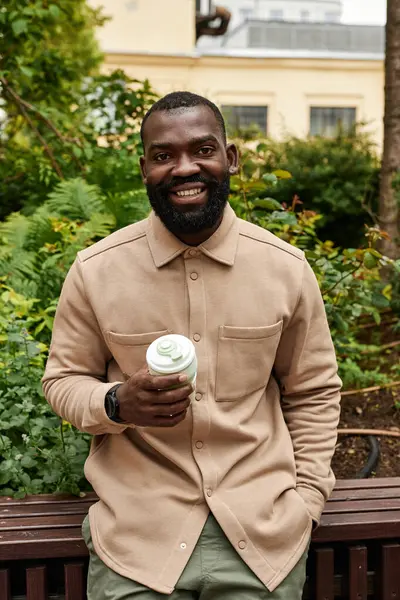 Pionowy Portret Uśmiechniętego Czarnego Mężczyzny Trzymającego Filiżankę Kawy Miejskim Ogrodzie — Zdjęcie stockowe