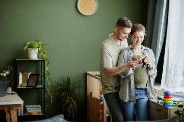 Mutlu genç çift çocuklarının doğumuna hazırlanıyor. Odada giysilerini hazırlıyorlar.