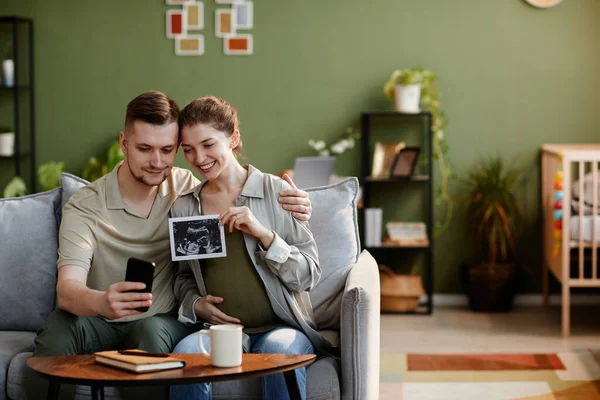 Young Couple Sitting Sofa Living Room Showing Ultrasound Image Video — Stock Photo, Image