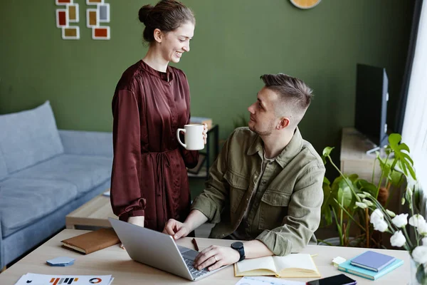 Young Woman Bringing Cup Coffee Her Boyfriend While Working Online — Stock Photo, Image