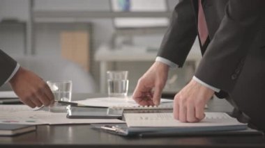 Resmi takım elbiseli iki tanınmayan yöneticinin dijital tablet üzerindeki sunumlarını tartışırken, aynı zamanda parlak modern ofiste masabaşında çalışırken.