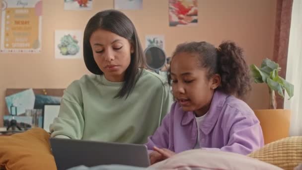 在生机勃勃的儿童卧室里 年轻的比拉尔妇女和她漂亮的10岁女儿坐在笔记本电脑旁聊天时 提着她的腰 — 图库视频影像