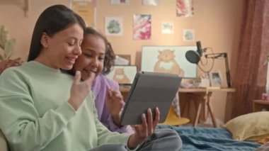 Afrika kökenli Amerikalı genç anne ve reşit olmayan kızının dijital tablet ekranda el sallayıp gülümsemesi ve evden görüntülü konuşma.