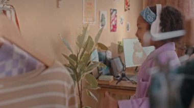 Orta boy Afro-Amerikan gen kız kablosuz kulaklık takıyor aynanın önünde dans ederken gündüz vakti canlı çocukların yatak odasında.