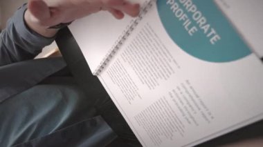 Orta yaşlı, beyaz iş adamının oturma odasındaki kanepede otururken mali raporunu analiz eden el kamerası görüntüsü.