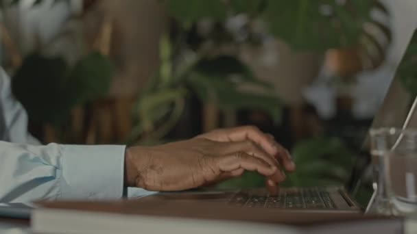 ノートパソコンのキーボードにタイピングする認識できないビジネスマンのブラックハンドのクローズアップ — ストック動画