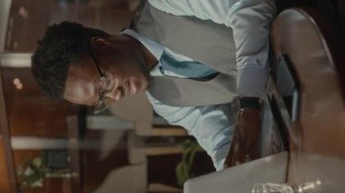 Afrika kökenli Amerikalı iş adamının gece ofiste çalışırken dizüstü bilgisayar kullanırken çekilmiş belden yukarı pozu.